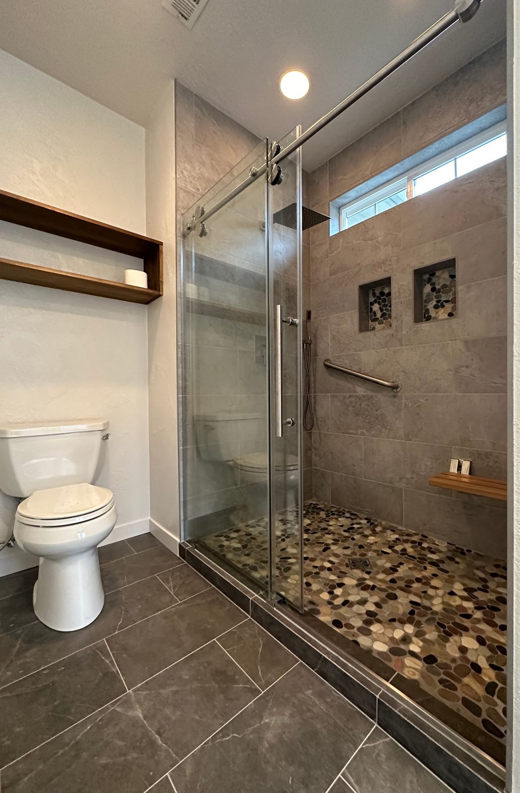 Finished custom tile walk-in shower with river-pebble floor and sliding glass door — Eagle Point bathroom remodel