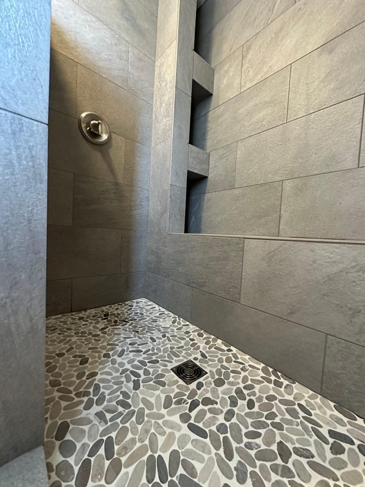 Custom tile walk-in shower with built-in niche shelves and pebble-stone floor β Medford bathroom remodel